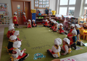 dzieci siedzą na dywanie w kole